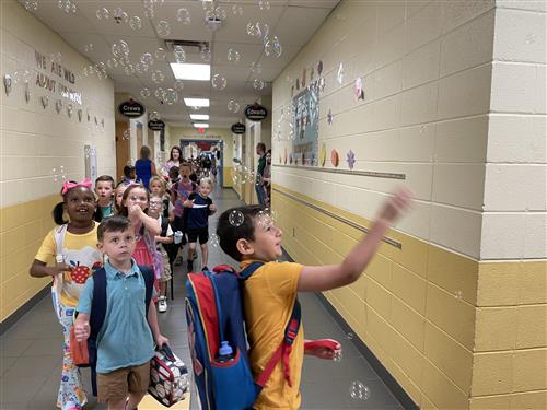 students walking through  a hall of bubbles in the air